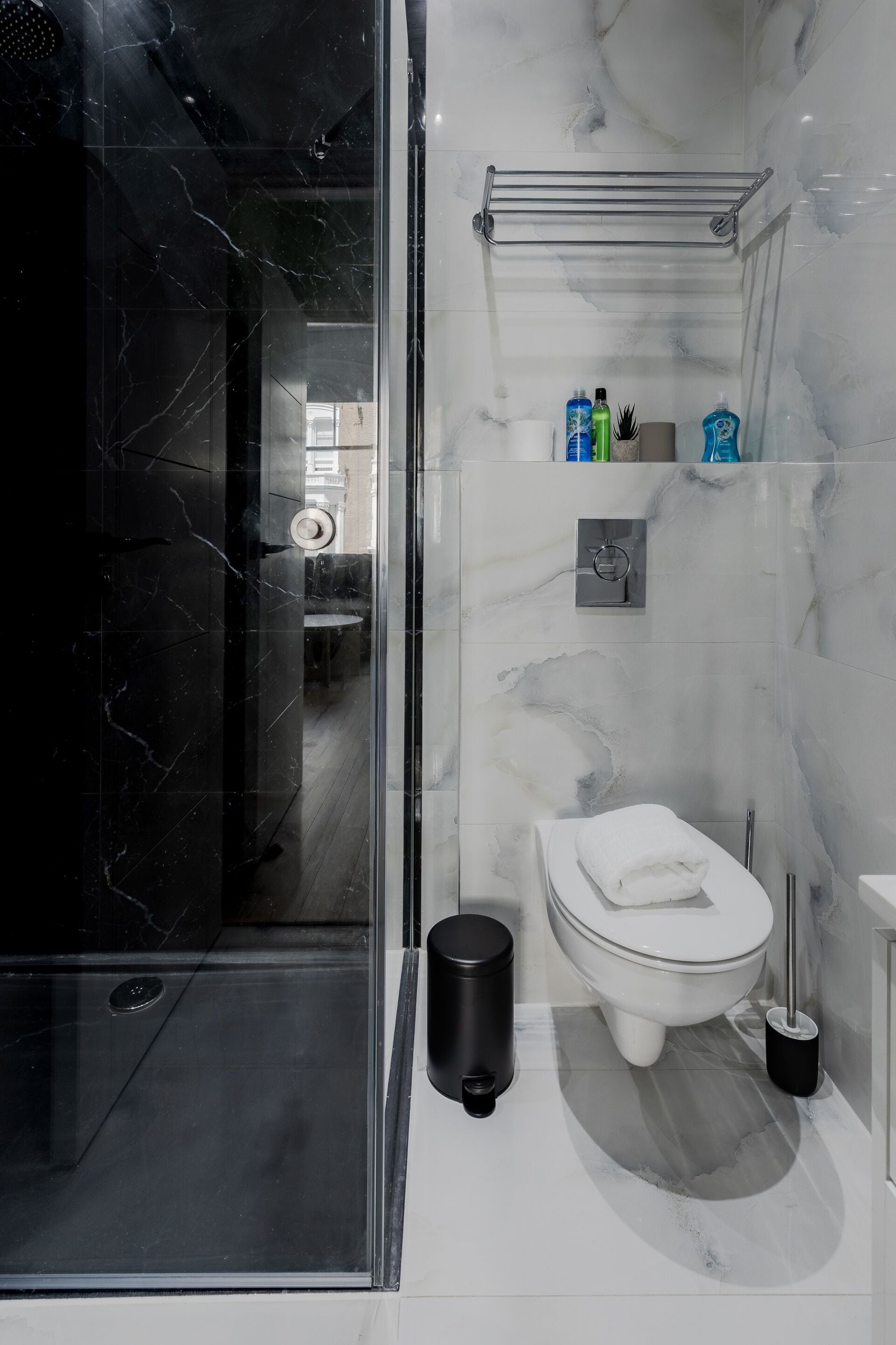 Een moderne badkamer met een douchecabine van glas, een toilet, een wastafel en een marmeren spatwand.