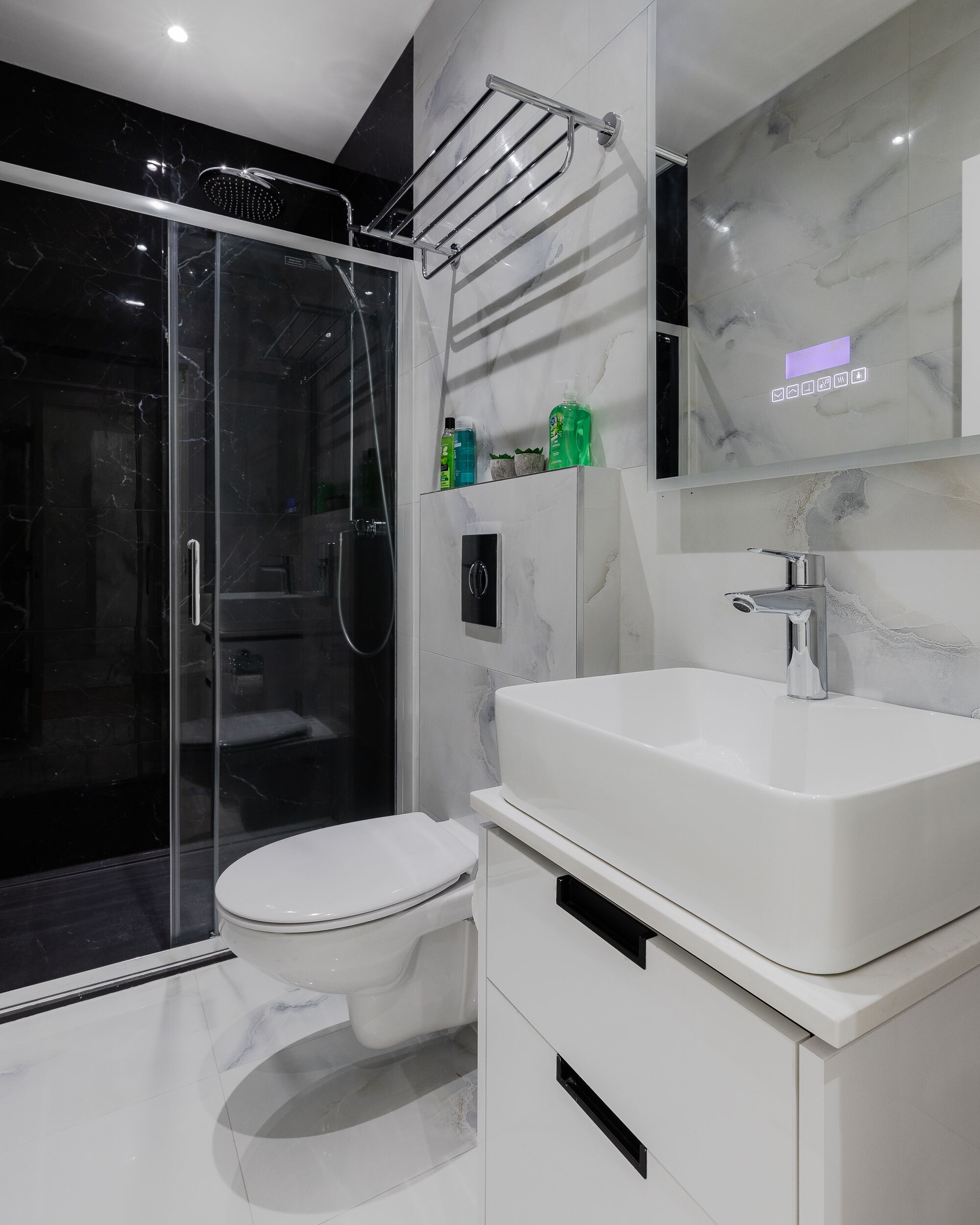 A modern bathroom with a glass-enclosed shower, a white sink, and a toilet.