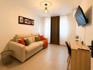 A living room with a sofa, a coffee table, a TV, a desk, and a globe.