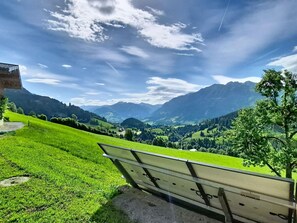 A bench overlooking a valley with mountains in the distance.