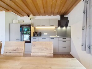 A modern kitchen with grey cabinets, a built-in oven, and a wooden ceiling.