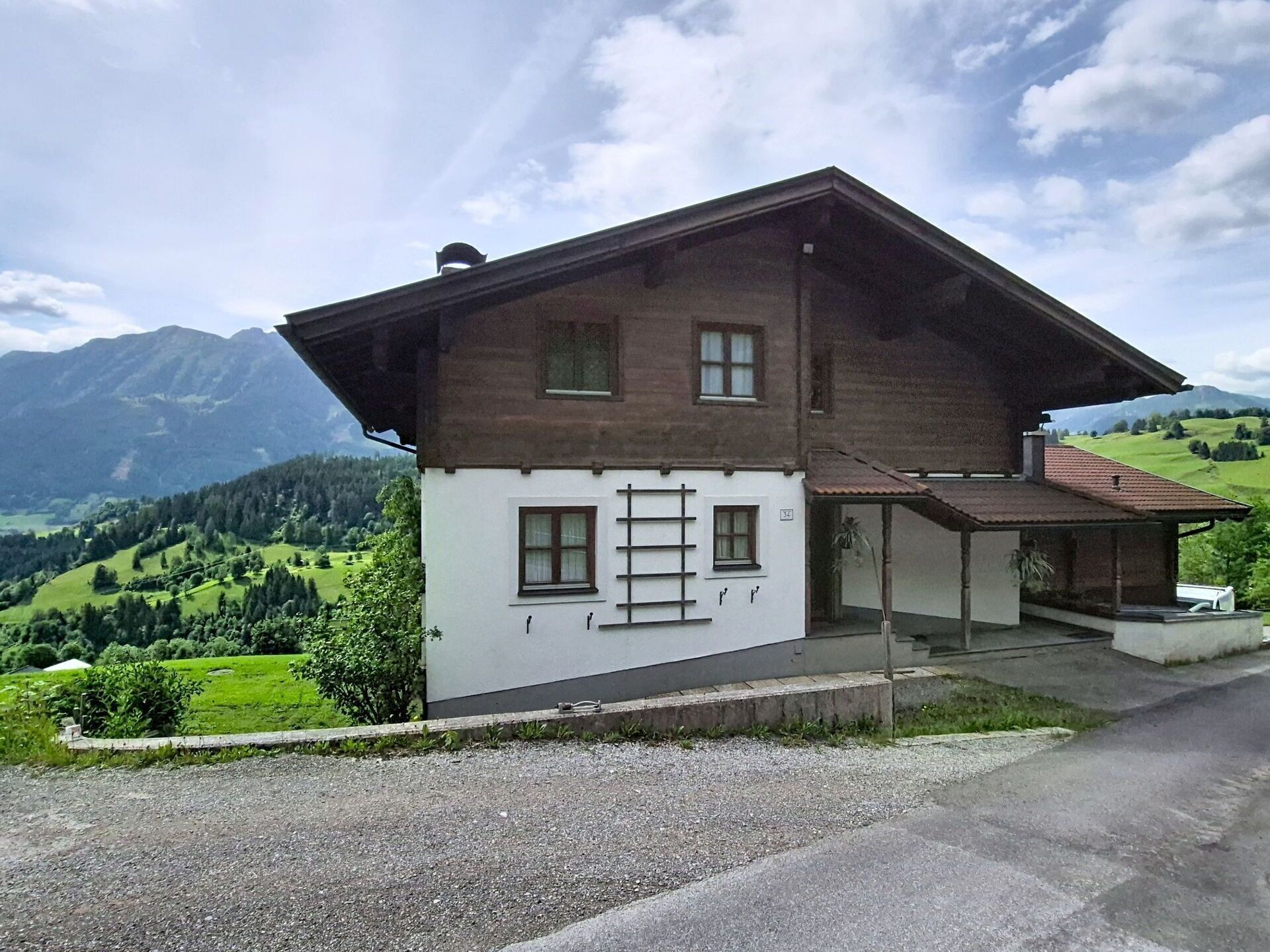 Une maison à deux étages, dotée d’un toit en pente, d’un porche et offrant une vue sur un paysage montagneux.