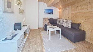 Una sala de estar moderna con techo de madera, un sofá gris, una mesa de centro blanca y un cuadro enmarcado en la pared.