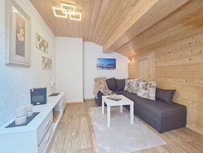 Ein modernes Wohnzimmer mit Holzboden, einem grauen Sofa, einem weißen Couchtisch und einem gerahmten Bild an der Wand.