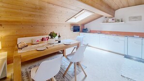 Un interior de madera con una mesa de comedor, sillas, una zona de cocina y un tragaluz.