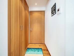 Ein Flur mit Holzausbau, einer Tür, einem Wandthermostat und einem gemusterten Teppich.