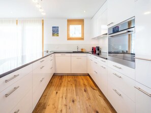 Eine moderne Küche mit weißen Schränken, Holzboden und einem eingebauten Ofen.