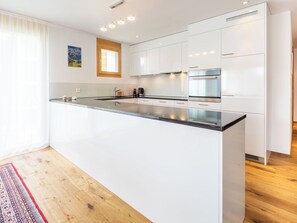 Eine moderne Küche mit weißen Schränken, einer großen Kochinsel, Edelstahlgeräten und Holzboden.
