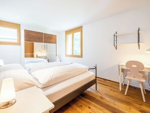 Ein modernes Schlafzimmer mit Bett, Nachttischen, Schreibtisch und Stuhl.