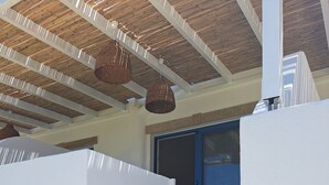 Un escalier menant à une porte dotée d’un cadre bleu, des murs blancs et un plafond en bois orné de suspensions fleuries.