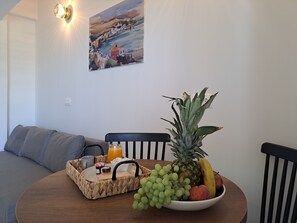 Ein Esstisch mit einer Obstschale, einer gewebten Ablage für Gewürze und einem Bild an der Wand.