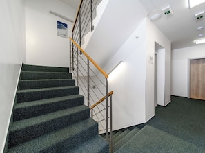 Eine Treppe mit hölzernem Geländer, Teppichstufen und einer weißen Wand mit einer Tür und einem Schild.