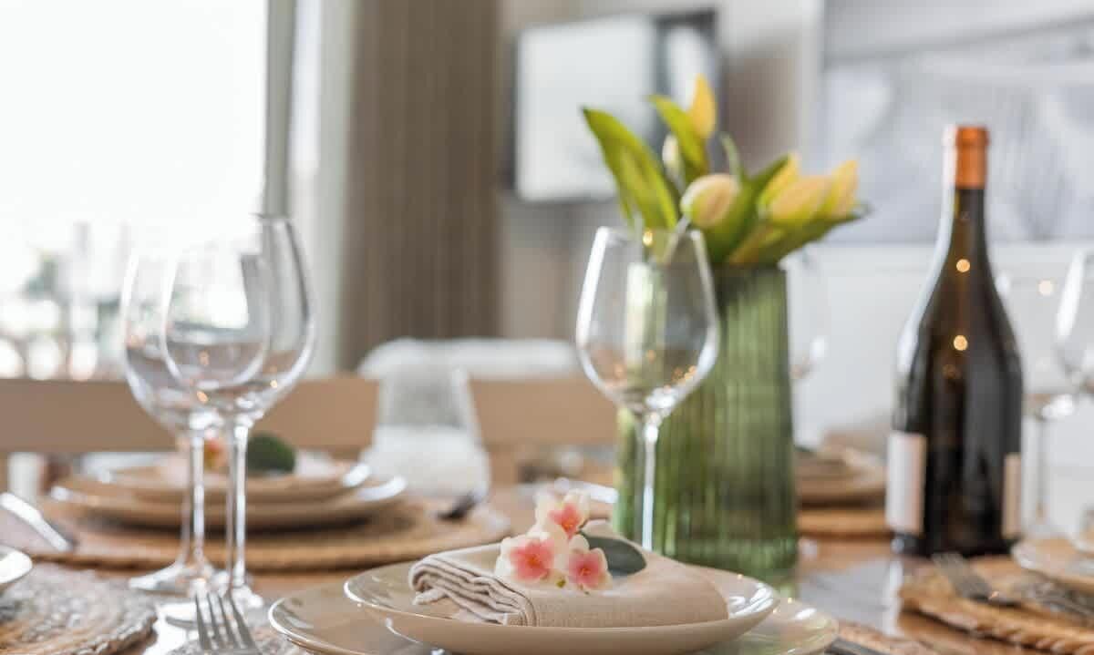 A dining table set with plates, cutlery, and a bottle of wine.