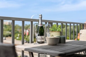 A balcony with a bottle of RENTUS wine, two glasses, a bowl, and a potted plant. - Droom Aan Zee-coastal stay close to beach and town (Nieuwpoort)
