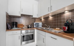 A kitchen with white cabinets, a microwave, a coffee maker, and a kettle. - Droom Aan Zee-coastal stay close to beach and town (Nieuwpoort)