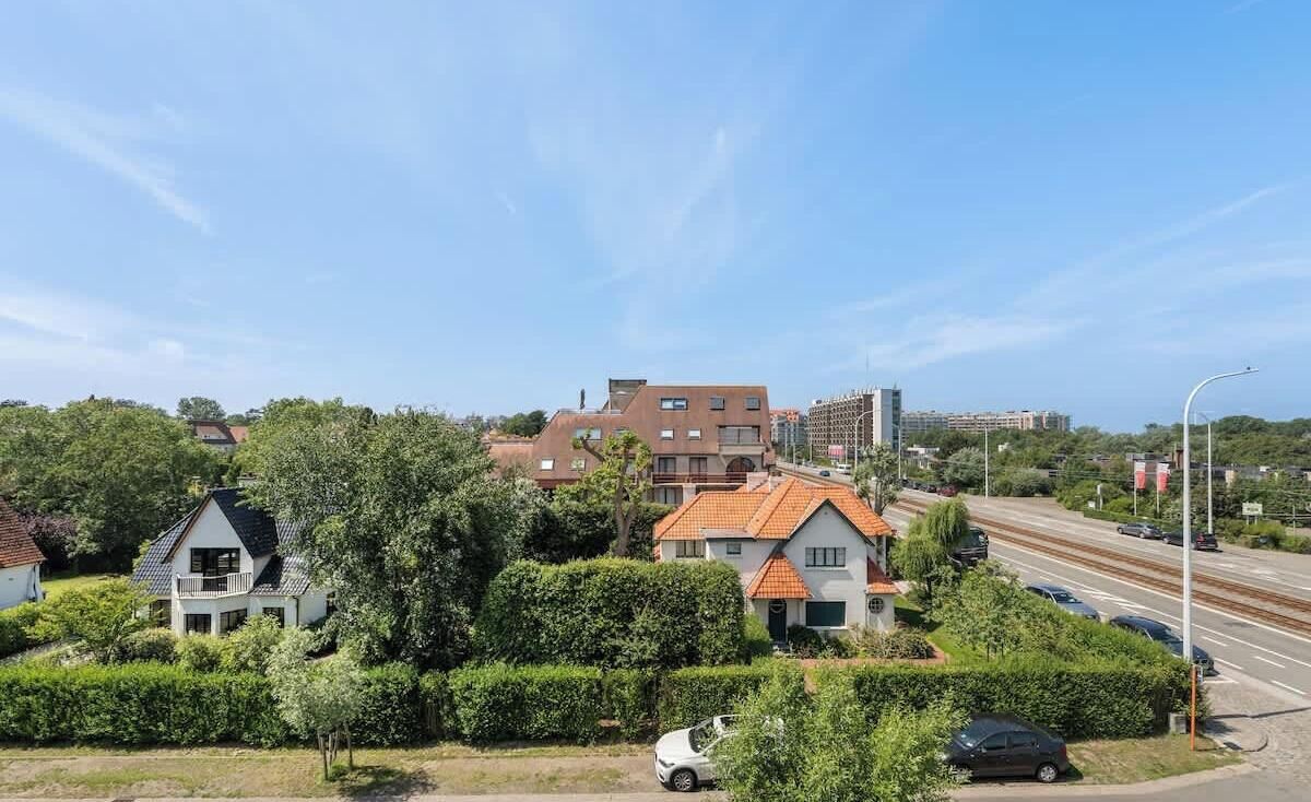 A residential area with houses, a railway track, and a clear sky.