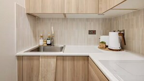 Eine moderne Küche mit Holzschränken, einer Edelstahl-Spüle und einer weißen Arbeitsplatte.