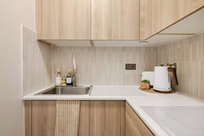 Eine Küche mit Holzausstattung, einer weißen Arbeitsplatte, einem Spülbecken und einer Kaffeemaschine.