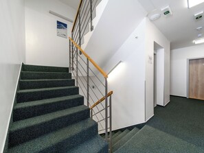 Eine Treppe mit hölzernem Geländer, Teppichstufen und einer weißen Wand mit einer Tür und einem Schild.