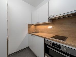 Eine moderne Küche mit weißen Schränken, einer Holzarbeitsplatte, einer Edelstahl-Spüle und einem Backofen.
