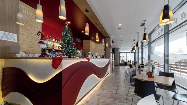 Un espace bar moderne agrémenté d’un sapin de Noël, de touches de bois et offrant une vue sur l’extérieur grâce à de grandes fenêtres.