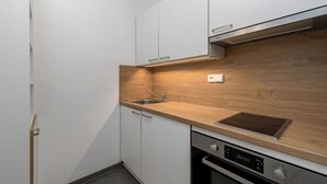Une cuisine moderne avec des armoires blanches, un plan de travail en bois, un évier en acier inoxydable et un four.