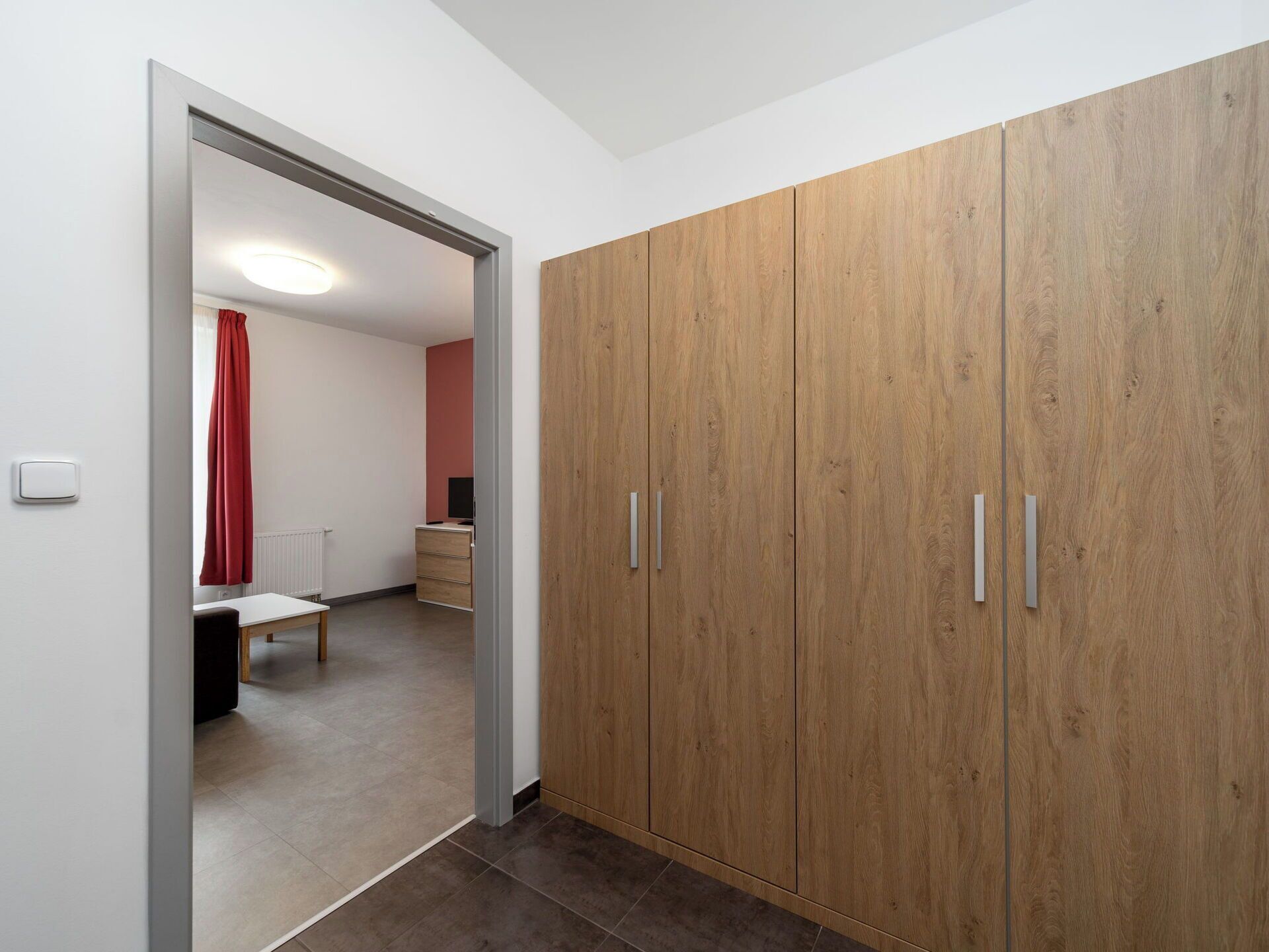Ein Zimmer mit Kleiderschrank, Bett, Schreibtisch und Heizkörper.