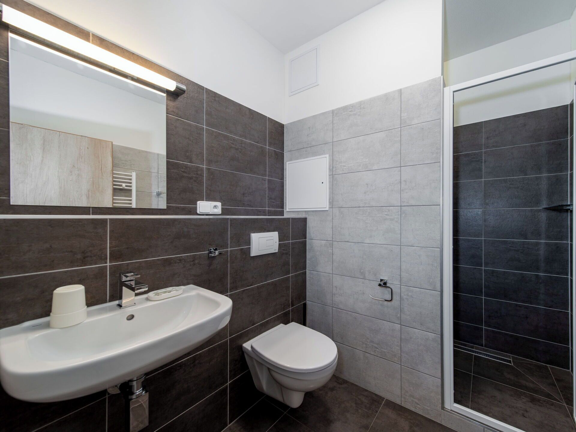 Un baño moderno con lavamanos, inodoro y ducha.