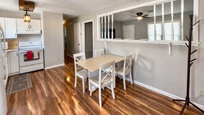 Une cuisine avec des meubles blancs, une cuisinière et un coin repas comprenant une table et des chaises.