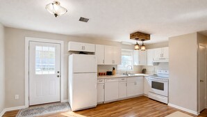 Une cuisine avec des meubles blancs, un réfrigérateur, un lave-vaisselle, une cuisinière et un évier.