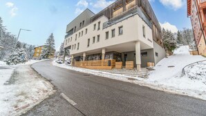 Et moderne hotel med overdækket indgang, en sneklædt gade og en klar himmel.