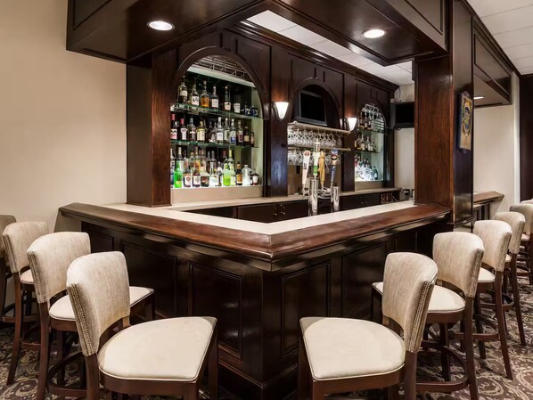 A bar area with a counter, multiple chairs, and shelves stocked with bottles.
