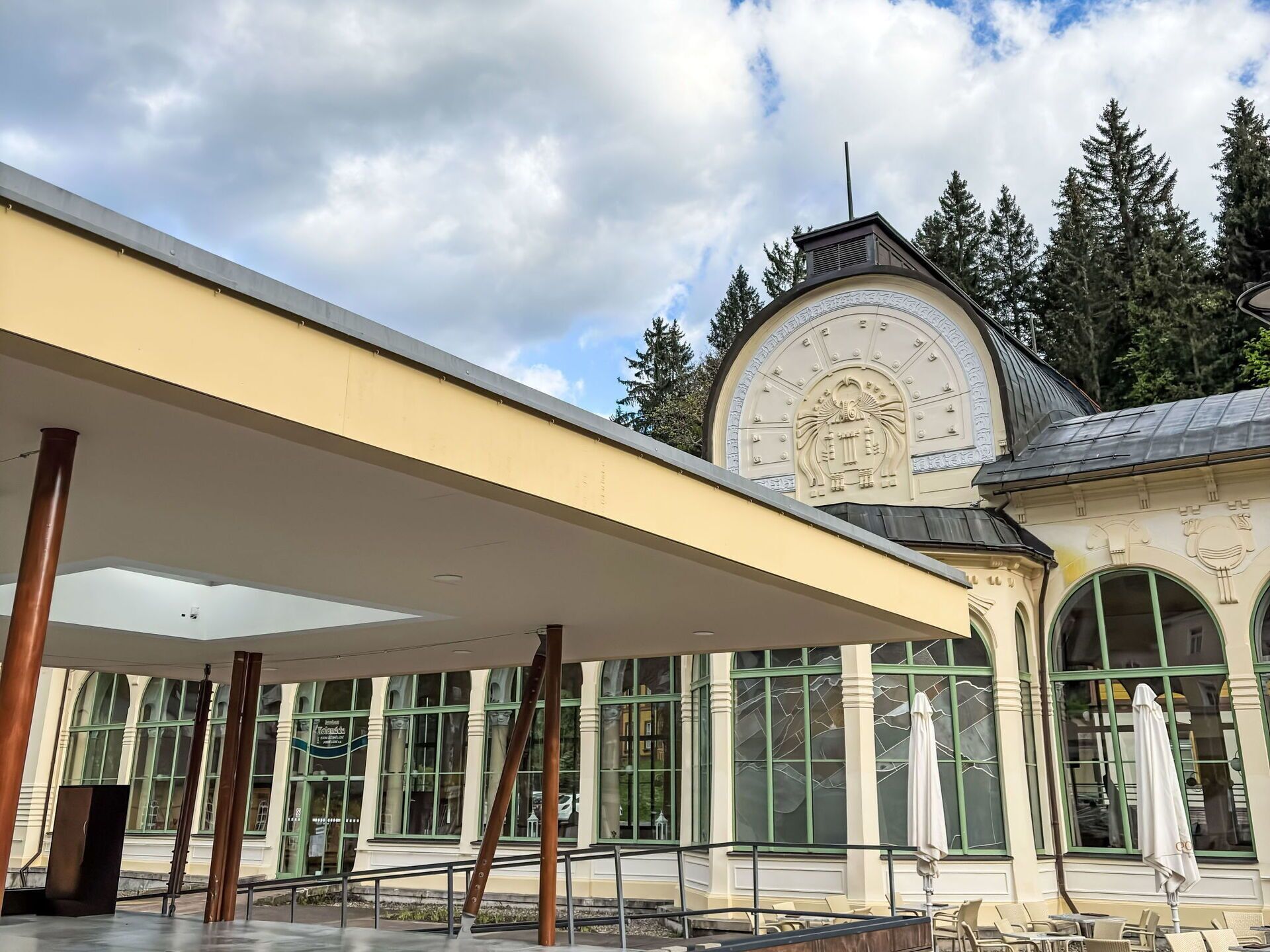 Ein überdachter Außenbereich mit einem Gebäude, das große Fenster und eine dekorative Fassade hat.