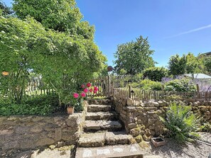 A stone staircase leading up to a garden area with lush greenery and flowering plants.