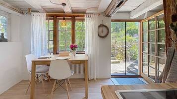 Ein Essbereich mit Tisch, Stühlen, einer Vase mit Blumen und Blick durch große Fenster.