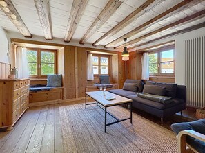 A cozy cabin interior with a wooden floor, a sofa, a table with a glass, and a dresser.