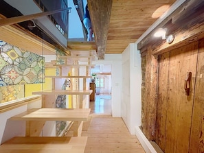 Una scala in legno con ringhiera in vetro conduce a una stanza con parete decorata e porta in legno.