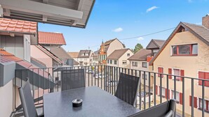 Ein Balkon mit Tisch und Stühlen, der auf eine Wohnstraße mit Häusern blickt.