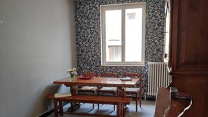Ein Schlafzimmer mit einem Bett, einem Holztisch mit Stühlen, einem Heizkörper und einem Fenster.