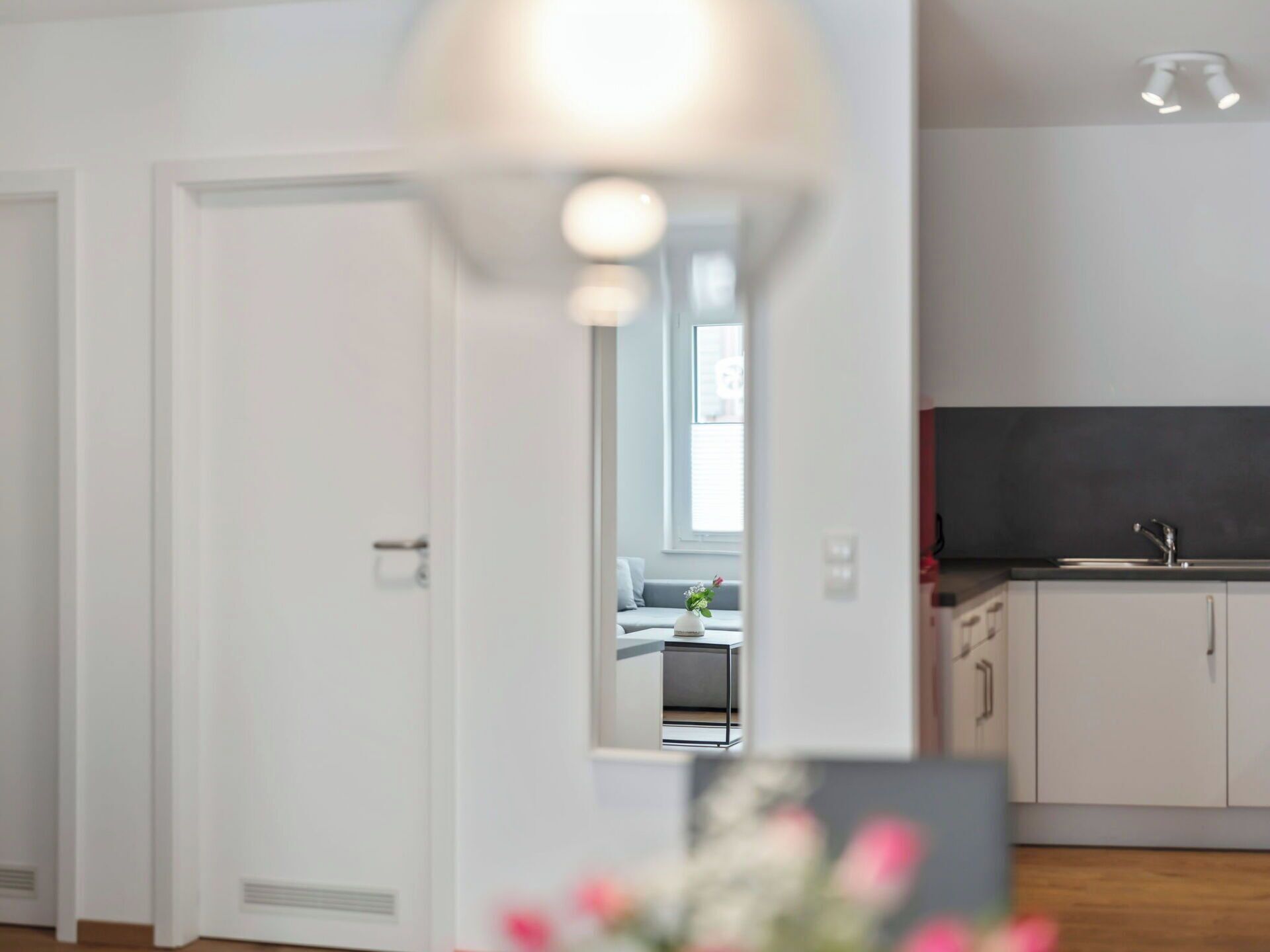Een moderne keuken met witte kasten, een zwart aanrecht en een raam boven de spoelbak.