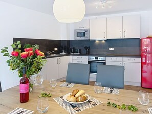 Une cuisine moderne avec des meubles blancs, un four à micro-ondes et un réfrigérateur rouge.