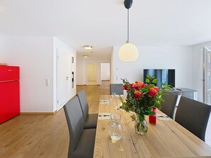 A dining area with a wooden table, chairs, a vase of flowers, and a red refrigerator. - Cosy apartment for 5 guests with WIFI, TV and balcony (Endingen)