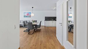 Moderni keittiö, jossa on valkoiset kaapit, musta työtaso ja sisäänrakennettu uuni.