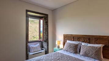 Un dormitorio con cama, mesita de noche, lámpara, ventana con vistas y cabecera de madera.