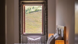 A bedroom with a view of terraced fields through a window.
