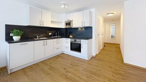 Eine moderne Küche mit weißen Schränken, einer schwarzen Arbeitsplatte und Holzboden.