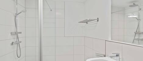 A modern bathroom with a glass shower enclosure, a white sink, and a mirror with integrated lighting.
