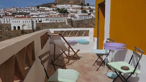 A balcony with a view of a town, a table with chairs, and a small round table. - Yellow House, Room 11_Family Room (Além Rio)