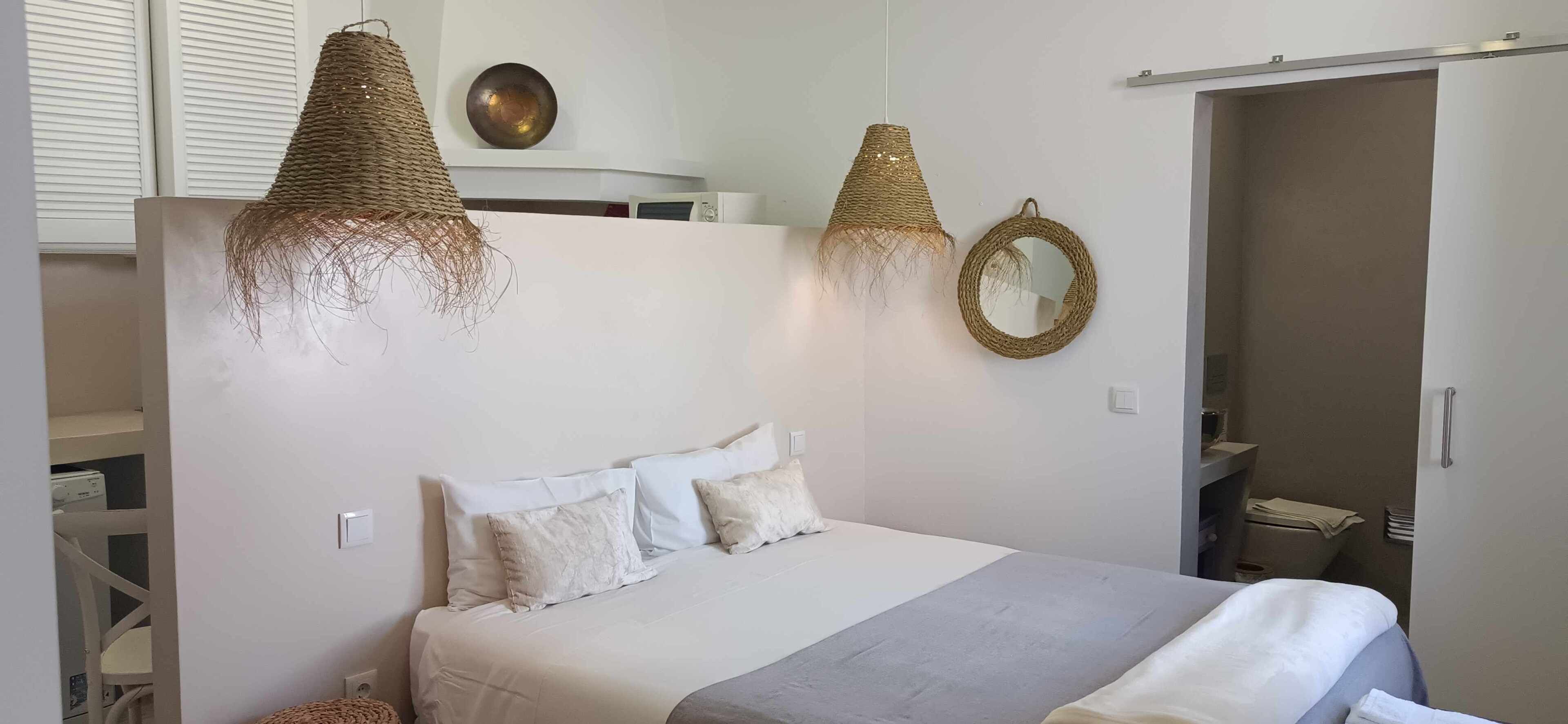 Une chambre à coucher avec un lit, deux lampes suspendues, un miroir et une armoire.
