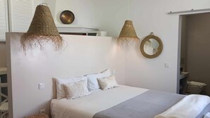 Ein Schlafzimmer mit einem Bett, zwei Pendelleuchten, einem Spiegel und einem Kleiderschrank.